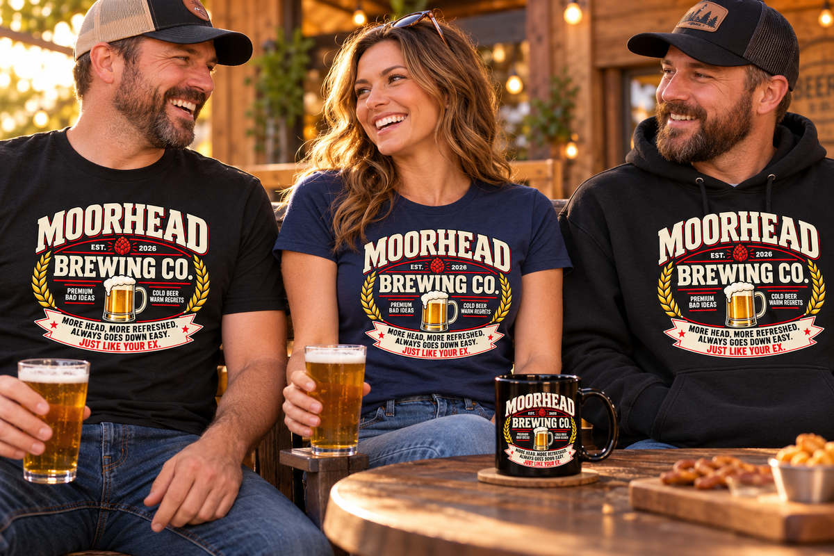 Adults wearing Moorhead Brewing Co. beer-crest T-shirts and a hoodie beside a matching black coffee mug on a pub patio.
